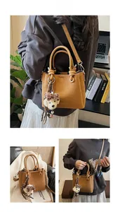 Close-up of brown suede mini square bag featuring dog charm and woven tassel details