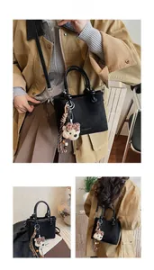 Detail of black textured bucket bag with plush puppy charm and tassel wood accent