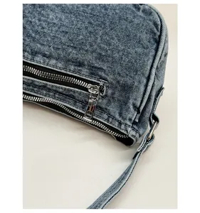 Detailed macro shot of silver metal zipper and hardware on blue washed denim handbag