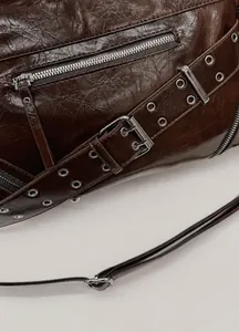 Detail of dark brown oil wax leather bag with metallic eyelets and buckle strap