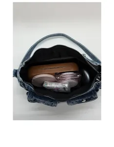 Spacious interior of retro washed denim handbag holding cosmetics and accessories