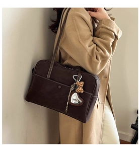 Detail of dark brown Boston shoulder bag featuring white contrast stitching and heart charm