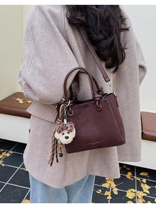 Brown frosted suede bucket bag with cute dog charm shown on shoulder for a winter commute
