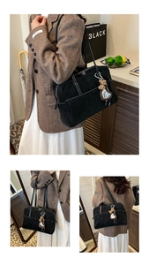 Detail of black matte leather tote bag with white contrast stitching and heart mirror charm