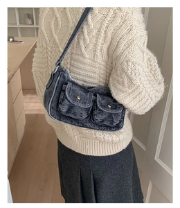 Detailed view of grey denim underarm bag with double utility pockets and metal buttons