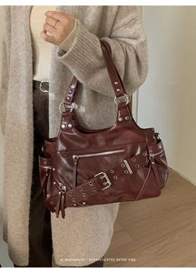 Close-up of retro burgundy faux leather shoulder bag with zippers and metal buckles