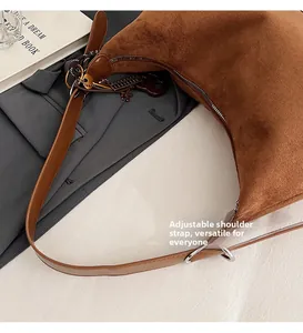 Dettaglio della borsa a mezzaluna in camoscio marrone con tracolla regolabile e charm