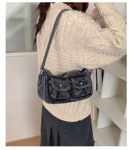 Detail of grey washed denim shoulder bag with utility pockets worn by a model