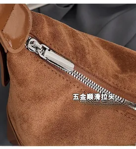 Dettaglio borsa in camoscio marrone con cerniera in metallo argento e tracolla in pelle