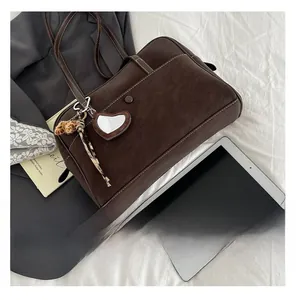 Detailed view of brown suede tote bag with contrast stitching and heart mirror charm