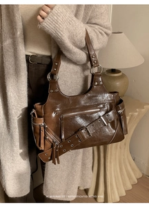 Close-up of vintage brown oil wax leather shoulder bag with metallic rivets and ring buckle