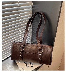 Gros plan détaillé du sac Boston marron foncé avec anneaux et rivets en métal argenté