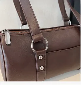 Detail of high-gloss silver hardware and premium brown leather texture on Boston bag