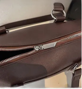 Detail of smooth silver metal zipper and lychee pattern leather on dark brown bag
