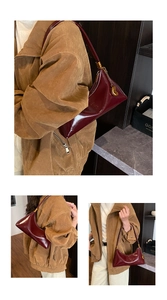 Gros plan du sac à bandoulière croissant rouge foncé brillant avec breloque dorée