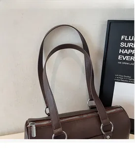 Detailed view of the dark brown leather shoulder bag with sturdy straps and metal rings