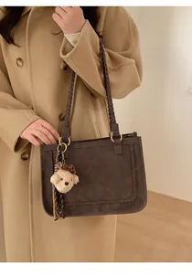Detail of dark brown tote bag with woven trim, rope handle and leopard bow bear charm