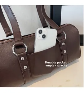 Detail of dark brown leather handbag featuring a practical front pocket and silver metal rings
