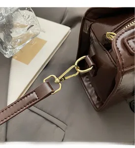 Détails des crochets dorés et anneaux en D sur sac à main en cuir verni marron brillant