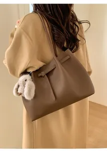 Detail of dark brown leather tote bag with silver buckle and white plush rabbit charm