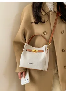 Detail of canvas bucket bag with leather trim, metal twist lock and branded lettering