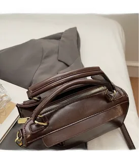 Détail du sac Boston vintage marron foncé avec fermetures éclair dorées et anses