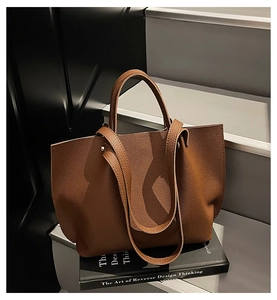 Close-up of brown pebbled leather tote bag showing rich texture on dark stairs