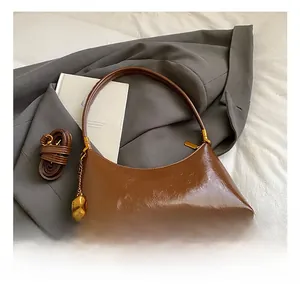 Détail d'un sac à bandoulière en cuir marron brillant avec fermeture éclair dorée