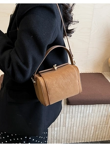 Detail of vintage brown box bag featuring golden metal clasp and premium leather texture
