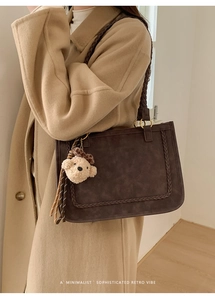 Detail of retro dark brown tote bag featuring woven straps and cute plush bear charm