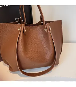 Detail of brown litchi pattern leather tote bag with gold rivets and soft texture