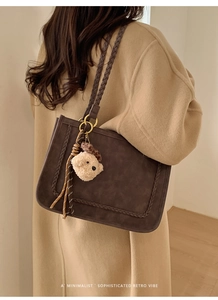Brown faux suede tote bag with woven trim and cute bear charm shown on shoulder