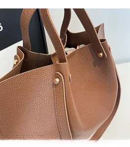 Close-up of caramel brown lychee leather tote bag featuring gold cylindrical rivets