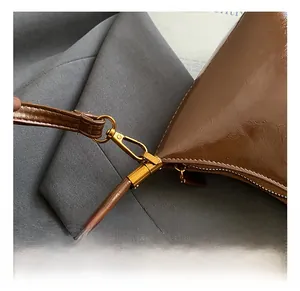 Détail du crochet en laiton vintage et de la bandoulière en cuir marron poli