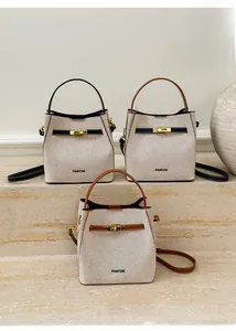 Detailed view of canvas bucket bags in black, blue and brown with leather trim and gold locks