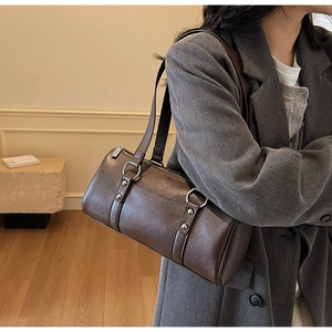 Deep brown oil-waxed leather Boston bag shown on shoulder with minimalist business attire
