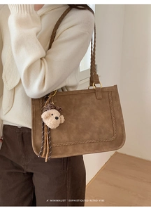Detail of retro brown suede tote bag with woven trim and plush bear charm accessory