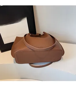 Detail of a brown lychee pattern leather tote bag with an adjustable long shoulder strap
