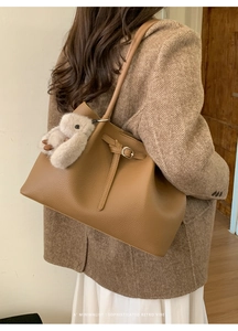 Brown lychee leather tote bag featuring an adjustable strap and a plush bunny charm