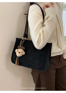 Detail of black suede tote bag featuring woven texture edges and cute bear charm accent