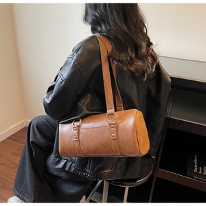Vue détaillée du sac polochon en cuir marron avec anneaux métalliques et rivets décoratifs