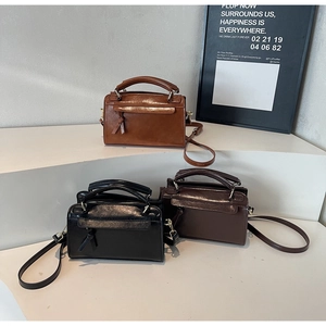 Sacs Boston en caramel, noir et café foncé sur des présentoirs minimalistes