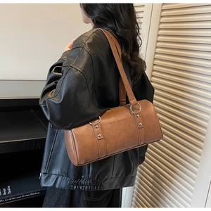 Sac cylindrique en cuir marron porté à l'épaule montrant la taille et les lanières souples