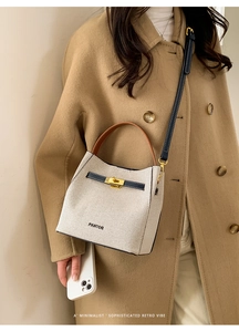 Detail of canvas bucket bag with leather trim and gold metal twist lock closure