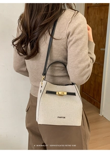 Rear view of a model wearing a chic cream bucket bag with black leather straps and gold lock