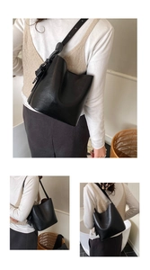 Detail view of the matte black leather bucket bag with an adjustable strap and side knot