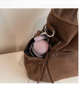 Detalle de bolso saco de ante marrón mostrando gran capacidad con un paraguas plegado