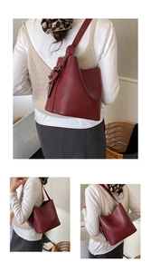 Detail view of a large red bucket bag with side knot decor and long shoulder strap