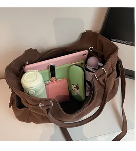 Detalle del interior de gran capacidad de un bolso tote marrón oscuro con artículos diarios