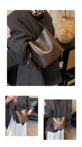 Close-up of brown vintage bucket bag with glossy PU leather texture and side buckle detail